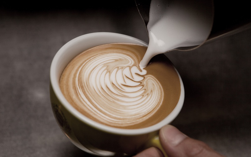 Barista verziert Kaffee mit Milchschaum-Muster